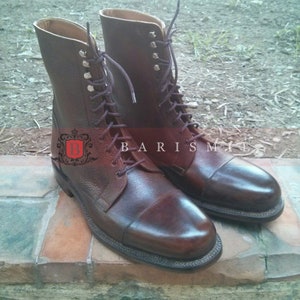 May include: A pair of brown leather lace-up boots with a cap toe. The boots have a textured leather upper and a contrasting brown leather heel.
