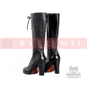 May include: A pair of black leather knee-high boots with lace-up detailing and high heels. The boots have a platform sole and a polished finish, with a wooden-look heel. The boots are displayed against a white background.