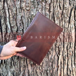 May include: A brown leather notebook with the word "BARISM" embossed on the front cover.
