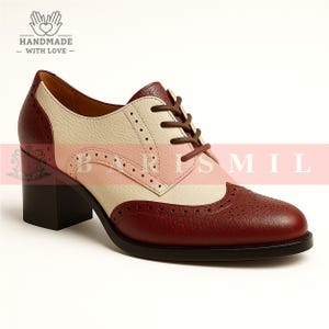 K&ouml;nnte beinhalten: Zweifarbiges Oxford-Schuh aus Leder mit Blockabsatz. Der Schuh hat weinrote, cremefarbene und rosa Eins&auml;tze mit dekorativen Perforationen. Braune Schn&uuml;rsenkel und eine schwarze Sohle. Handgefertigt.