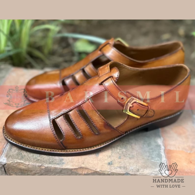 Puede incluir: Un par de sandalias de cuero marr&oacute;n con punta cerrada y laterales abiertos. Las sandalias tienen una correa en la parte superior con una hebilla dorada. Las suelas son de color marr&oacute;n oscuro. Hecho a mano con amor.