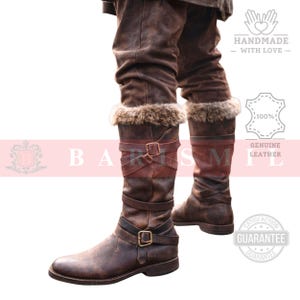 May include: Brown leather knee-high boots with fur trim at the top. The boots have multiple straps with buckles and a distressed finish. The image includes text that says "HANDMADE - WITH LOVE" and "100% GENUINE LEATHER".