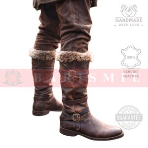 May include: Brown leather knee-high boots with fur trim at the top. The boots have multiple straps with buckles and a distressed finish. The image also includes text that says "Handmade with Love" and "Genuine Leather".