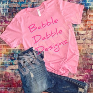 May include: Pink t-shirt with the text "Babble Dabble Designs" in pink lettering.