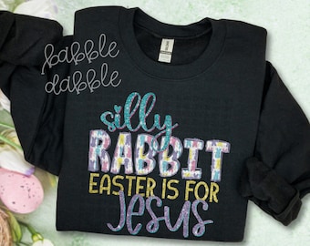 Könnte beinhalten: Schwarzer Pullover mit einem glitzernden Design, auf dem "silly rabbit easter is for jesus" steht.