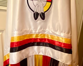 Peut inclure: Châle en satin blanc avec un symbole amérindien coloré et une bordure en franges. Le symbole est un cercle avec quatre couleurs : noir, blanc, rouge et jaune. Les franges sont dans les quatre mêmes couleurs.