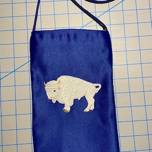 May include: A blue satin pouch with a white embroidered buffalo design. The pouch has a blue strap.