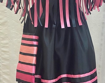 May include: A black dress with pink and black ribbon trim. The dress has a cape-like top with fringe and a skirt with horizontal stripes.