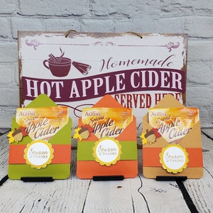 May include: Three small envelopes with a fall theme, each containing a packet of spiced apple cider mix. The envelopes are decorated with fall leaves, acorns, and the text "Season of Thanks".