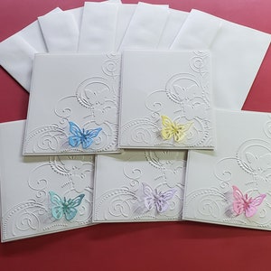 May include: Five white cards with embossed designs and a butterfly cutout on each. The butterflies are in different colors: blue, yellow, purple, and pink.