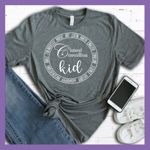Puede incluir: Camiseta gris con un dise&ntilde;o circular blanco que dice "Classical Conversations kid" y est&aacute; rodeado de las palabras "Bible, Tin Whistle, Music, Art, Latin, Math, English, Timeline, Science, History, Geography, Presentations".