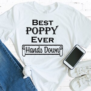 May include: White t-shirt with black text that reads "Best Poppy Ever Hands Down".