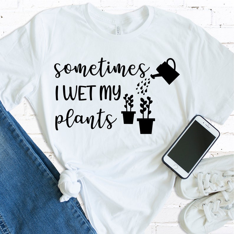 May include: White t-shirt with black text that reads "sometimes I WET my plants" and a black watering can pouring water on two black potted plants.