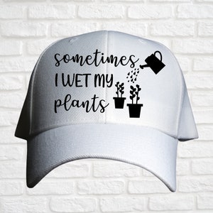 May include: White baseball cap with black text that reads "sometimes I WET my plants" and a black silhouette of a watering can pouring water on two potted plants.