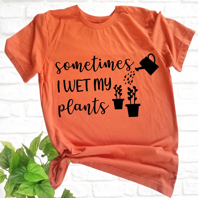 May include: Orange t-shirt with black text that reads "sometimes I wet my plants" and a graphic of a watering can watering three potted plants.