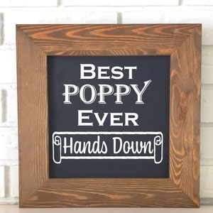 May include: A framed chalkboard sign with the text "Best Poppy Ever Hands Down" in white lettering on a dark blue background.