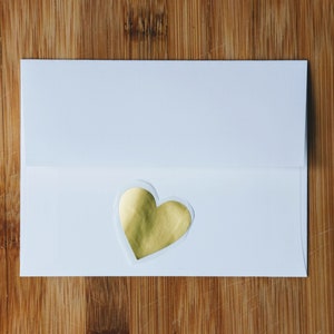 May include: A white envelope with a gold heart sticker on the front.