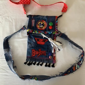 May include: A blue denim crossbody bag with a red, white, and blue patch, a red patch with the text "Bon Jovi", and a green and blue button. The bag has a red and white polka dot strap.