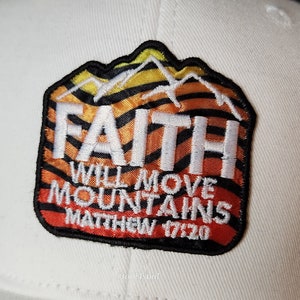 May include: White baseball cap with a colourful embroidered patch that says "FAITH WILL MOVE MOUNTAINS MATTHEW 17:20". The patch features a mountain range with a sunrise behind it.