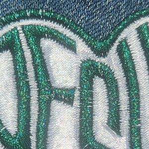 May include: Close-up of a green and white embroidered patch with the word "FREE" in a cursive font.