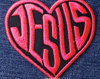 Op de afbeelding: Roze geborduurde patch in de vorm van een hart met het woord "JESUS" erin. De patch is op een blauwe denim achtergrond. De hashtag #tool4soul staat onder de patch.
