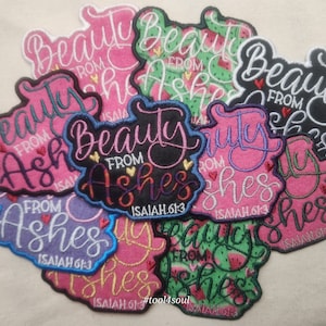 May include: A collection of embroidered patches with the phrase "Beauty from Ashes" and the Bible verse Isaiah 61:3. The patches are in various colors, including pink, purple, black, and green. Some patches feature a watermelon pattern.