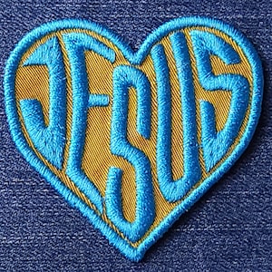 Peut inclure: Un patch brodé bleu en forme de cœur avec le mot "JESUS" à l'intérieur.