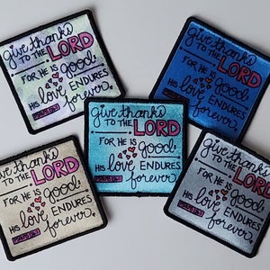 Peut inclure: Quatre patchs carrés avec des bordures noires et un fond blanc. Chaque patch a un fond de couleur différente avec le texte "Give thanks to the Lord, for he is good. His love endures forever." en lettres noires et roses. Le texte "Psalm 107:1" est également inclus sur chaque patch.
