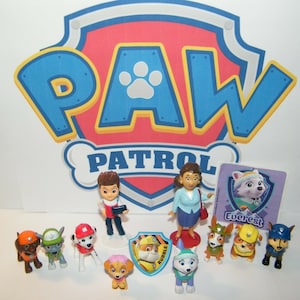 May include: A set of Paw Patrol figurines, including Chase, Marshall, Skye, Rubble, Rocky, Zuma, Everest, Ryder, and a female character. The figurines are made of plastic and are brightly colored. The set also includes a Paw Patrol logo and a card with the name "Everest" on it.