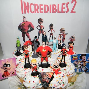 May include: A cupcake decorated with sprinkles and featuring figurines of the characters from the movie "Incredibles 2". The characters include Mr. Incredible, Elastigirl, Violet, Dash, Jack-Jack, Frozone, and Syndrome. The cupcake is topped with a small "Toy Story" sticker.