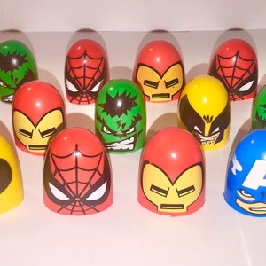 May include: A collection of Marvel superhero-themed egg-shaped toys. The toys feature characters like Spider-Man, Hulk, Iron Man, Wolverine, and Captain America. The color scheme includes red, green, yellow, and blue. A Green Goblin figure is also present.