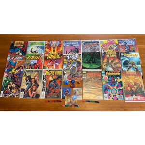 Peut inclure: Une collection de bandes dessinées mettant en scène divers super-héros, dont Captain Marvel, Daredevil et Flash. Les bandes dessinées sont disposées en rangées sur une surface en bois. Il y a aussi plusieurs petits jouets et bibelots éparpillés autour des bandes dessinées.