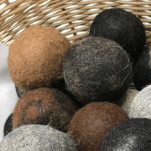 Peut inclure: Un panier en osier rempli de boules de séchage en laine de différentes nuances de brun, gris et noir. Les boules sont douces et moelleuses, parfaites pour ajouter une touche naturelle à votre routine de lavage.