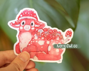 Peut inclure: Un autocollant rouge et blanc représentant un cerf de dessin animé avec un chapeau de champignon et des champignons poussant sur son dos. L'autocollant indique "Ivory Owl co" dans le coin inférieur droit.