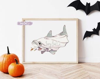Può includere: Una stampa artistica incorniciata raffigurante uno squalo grigio che indossa un costume da fantasma bianco. Lo squalo ha un'espressione amichevole ed è circondato da piccole caramelle colorate. Il testo Ivory Owl Co è visibile in corsivo.