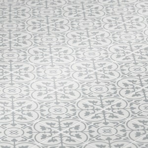 Puede incluir: Un azulejo de suelo blanco con un patrón repetido de diseños florales grises. El patrón es simétrico y crea un aspecto geométrico.