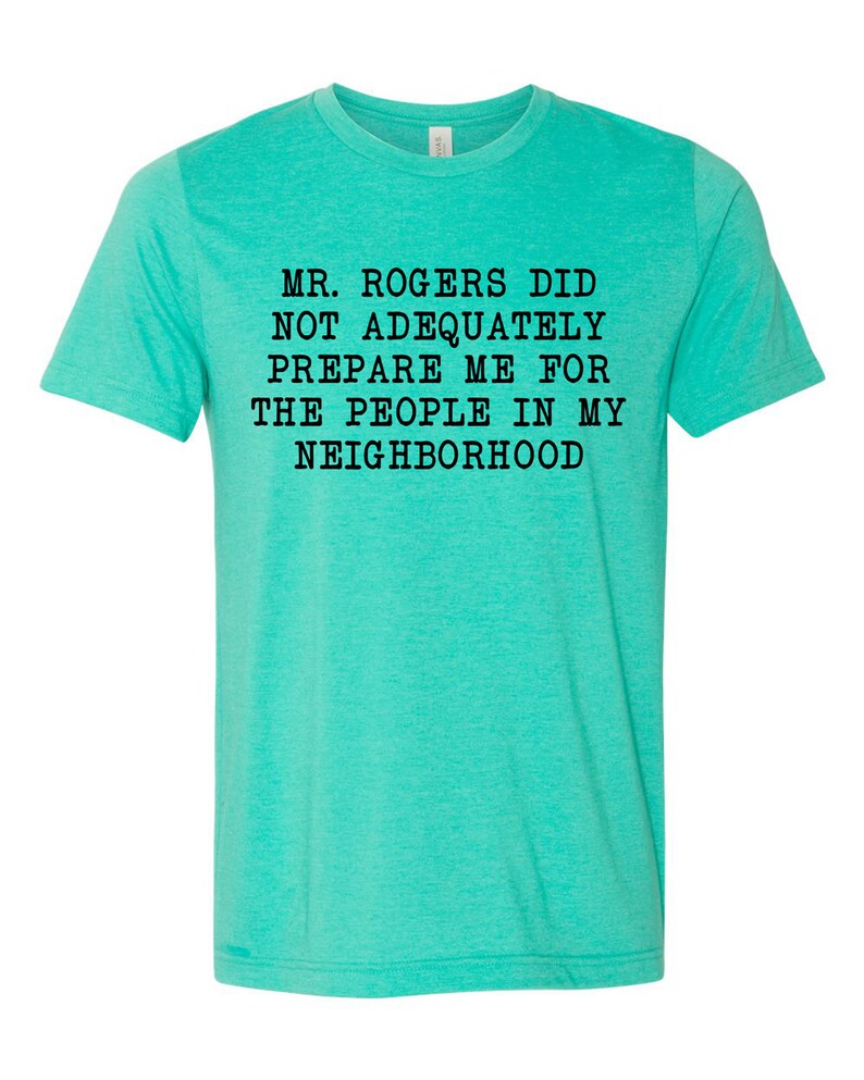 May include: A turquoise blue t-shirt with the text "Mr. Rogers did not adequately prepare me for the people in my neighborhood" printed in black.