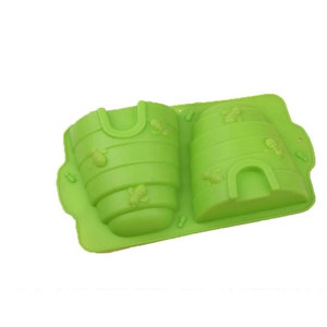 Puede incluir: Molde de silicona verde en forma de dos colmenas. El molde está diseñado para hacer golosinas con forma de panal.