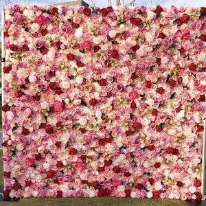 Può includere: Un grande muro floreale fatto di rose artificiali rosa, rosse e bianche. Il muro è composto da molti fiori singoli, creando un aspetto pieno e lussureggiante.