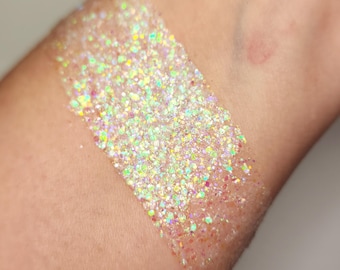 May include: A close-up of iridescent glitter on a person's arm. The glitter is a mix of white, silver, and rainbow colors.