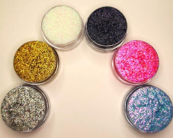 May include: Six small round jars of glitter, each containing a different color: gold, silver, white, black, pink, and blue.