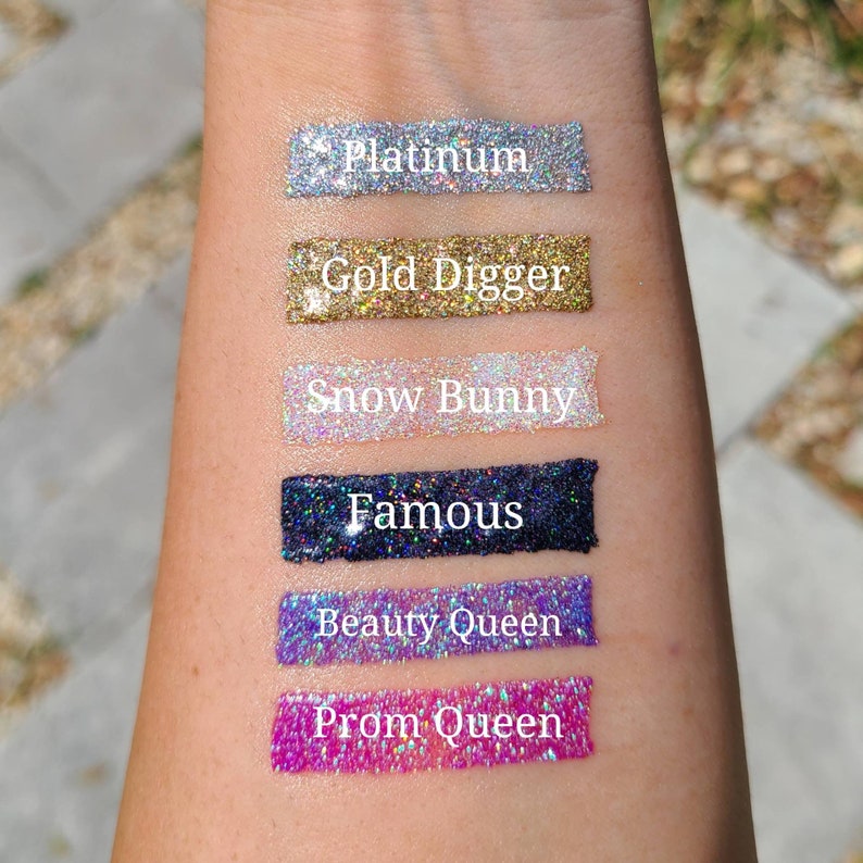 K&ouml;nnte beinhalten: Sechs verschiedene Glitzerproben werden auf dem Arm einer Person gezeigt. Die Proben sind mit "Platinum", "Gold Digger", "Snow Bunny", "Famous", "Beauty Queen" und "Prom Queen" beschriftet.