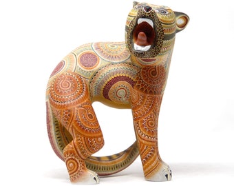 May include: A handcrafted wooden sculpture of a roaring cat, featuring intricate patterns in shades of orange, yellow, and brown. The cat's mouth is open, revealing its teeth and tongue. The sculpture is a unique piece of art.