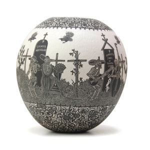 May include: A white ceramic pot with a black and white design of skeletons playing music and walking in a graveyard. The pot has a black and white floral design around the bottom.