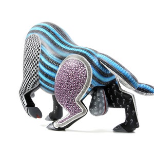 May include: A wooden bull sculpture with intricate carvings and a blue, black, and purple colour scheme. The bull is in a charging pose with its head lowered and horns pointed forward.