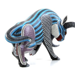 May include: A blue, black and white wooden bull sculpture with intricate geometric patterns. The bull is in a charging pose with its head lowered and horns pointed forward.