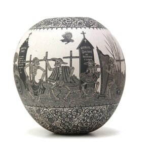 May include: A white ceramic sphere with a black and white design depicting skeletons in a procession. The design includes a cross, a tombstone with the text "NICOLAS QUELADA DE PADRON Y ESCRIBA", and a harp. The sphere is decorated with a black floral pattern around the edges.