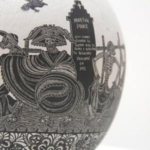 May include: Black and white ceramic skull with a black and white floral design. The skull is wearing a hat and has a skeletal face. The text on the tombstone reads "MARTHA POINCE ESTA TUMBA STUARDA TU CUERPO DIOS TU ALMA Y NUSTA TO RECUERDO DESCANSE EN PAZ".