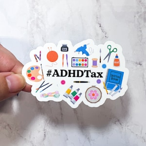 Op de afbeelding: Een witte sticker met een kleurrijke illustratie van verschillende knutselmaterialen, waaronder verf, garen, schaar, lijm en een schetsboek. De tekst "#ADHDtax" staat in zwarte letters.