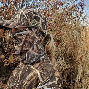 K&ouml;nnte beinhalten: Eine Person tr&auml;gt eine braune und beige Tarnjacke und eine braune und beige Tarnbaseballkappe mit dem Schriftzug "Duck Commander" auf der Vorderseite. Die Person tr&auml;gt eine braune und beige Tarnmaske.